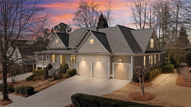 view of front of home with an attached garage, concrete driveway, and a shingled roof