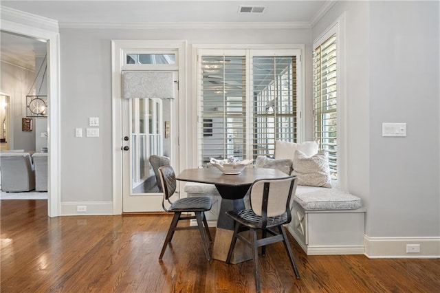 dining room with baseboards, wood finished floors, visible vents, and crown molding