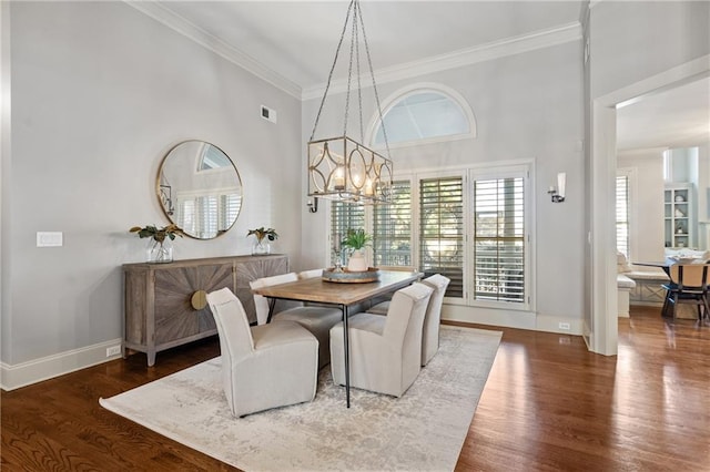 dining space featuring baseboards, ornamental molding, a chandelier, and wood finished floors