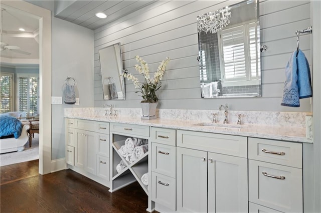 ensuite bathroom with double vanity, ensuite bath, a sink, and wood finished floors