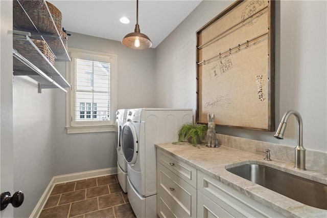 washroom with cabinet space, a sink, separate washer and dryer, dark tile patterned floors, and baseboards