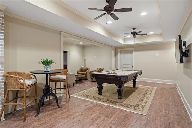 game room featuring billiards, baseboards, a raised ceiling, ornamental molding, and wood finished floors