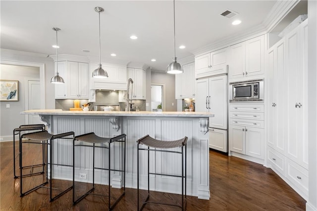 kitchen featuring white cabinetry, visible vents, a kitchen breakfast bar, and built in appliances