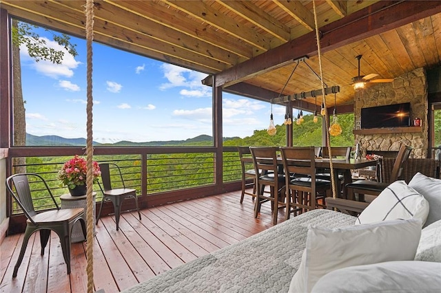 wooden deck featuring a mountain view and an outdoor stone fireplace