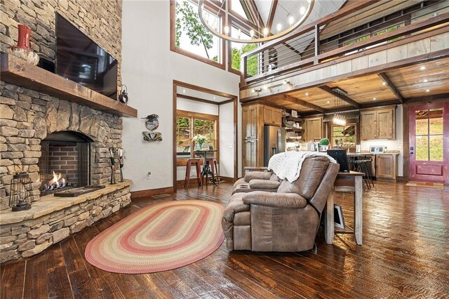 living room with a fireplace, an inviting chandelier, a high ceiling, wooden ceiling, and dark wood-type flooring