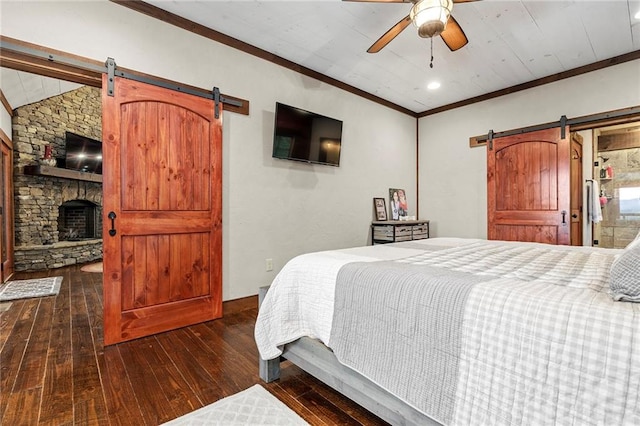 bedroom featuring a barn door, ceiling fan, ornamental molding, and dark hardwood / wood-style flooring