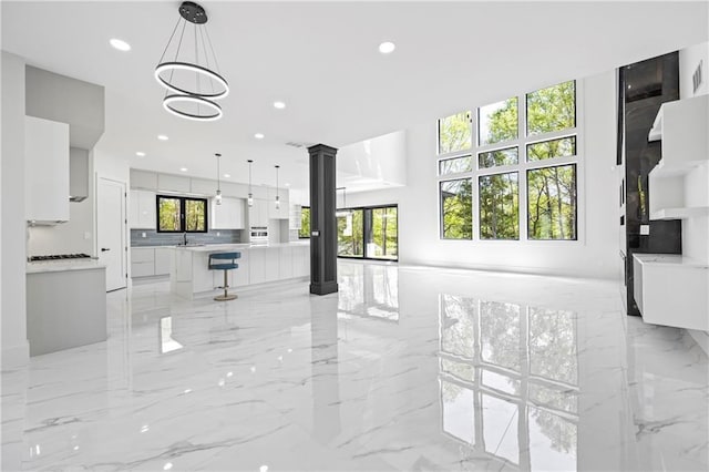 4238 Hamilton Mill Rd, Buford, GA 30519 - unfurnished living room with light marble finish floors, ornate columns, and recessed lighting