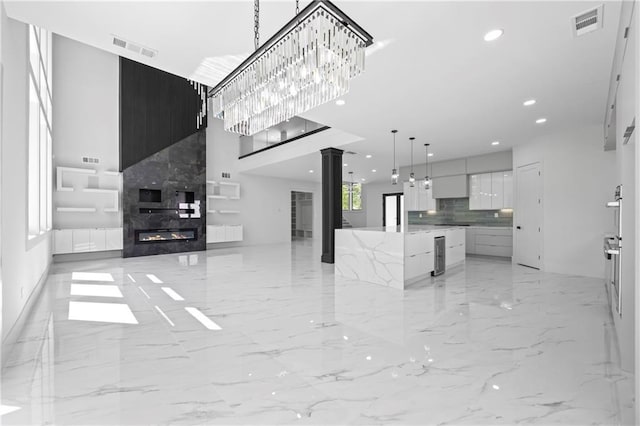 4238 Hamilton Mill Rd, Buford, GA 30519 - unfurnished living room featuring decorative columns, a towering ceiling, light marble finish flooring, a high end fireplace, and recessed lighting