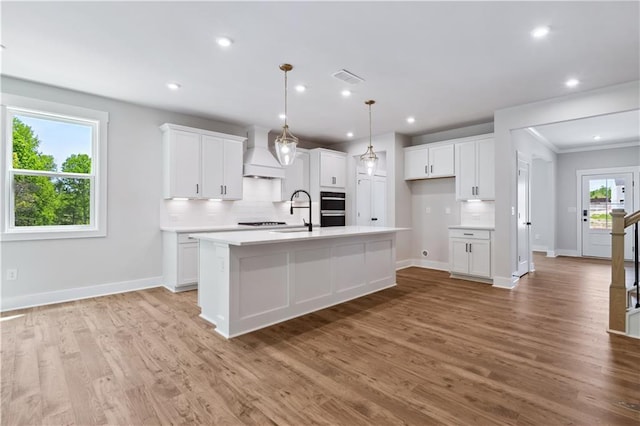 4002 Adler Cir, Buford, GA 30519 - kitchen with an island with sink, baseboards, decorative backsplash, and custom range hood