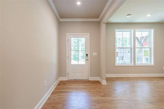 doorway to outside with ornamental molding and light wood-type flooring