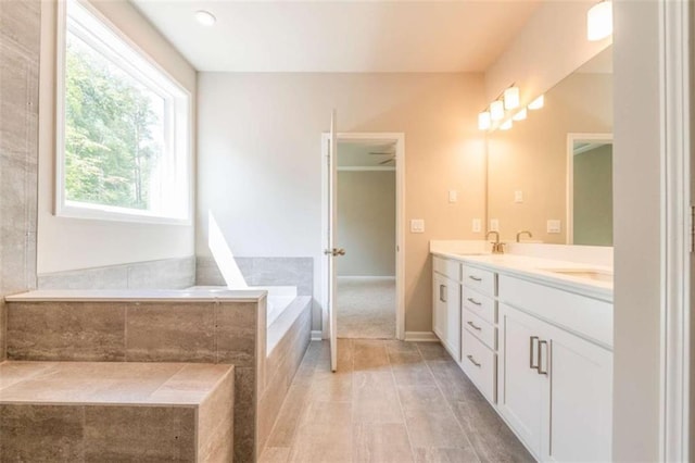 bathroom with vanity and tiled tub