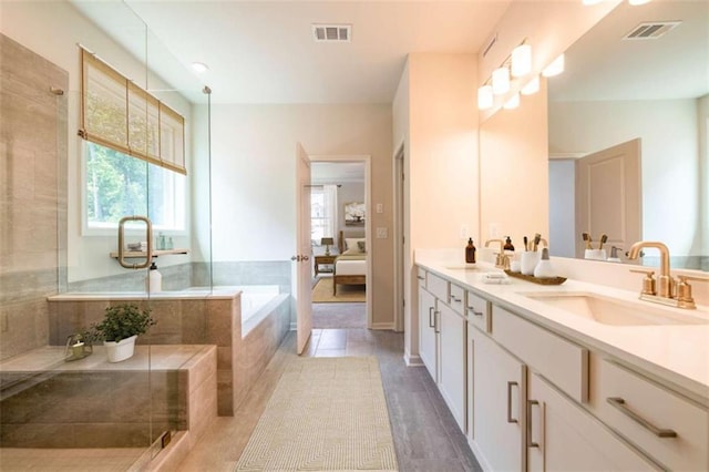 bathroom featuring tile patterned floors, tiled bath, vanity, and a healthy amount of sunlight