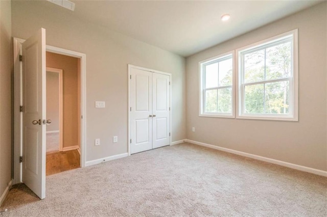 unfurnished bedroom with a closet and light colored carpet