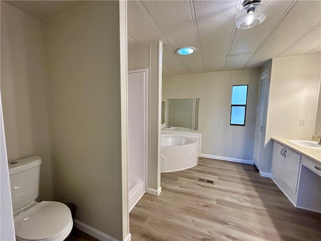 bathroom with toilet, wood finished floors, visible vents, vanity, and a closet