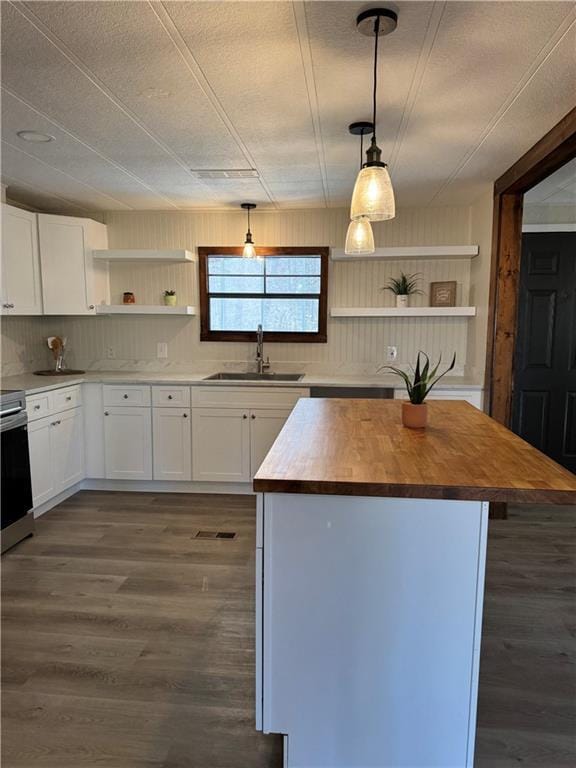 kitchen featuring open shelves, hanging light fixtures, a kitchen island, wood counters, and a sink