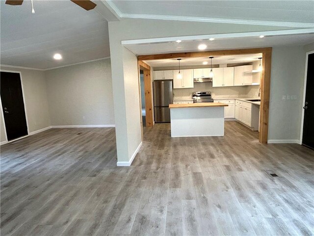 kitchen featuring white cabinetry, pendant lighting, ornamental molding, and appliances with stainless steel finishes