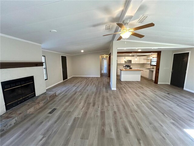 unfurnished living room featuring ceiling fan, ornamental molding, light hardwood / wood-style floors, and vaulted ceiling