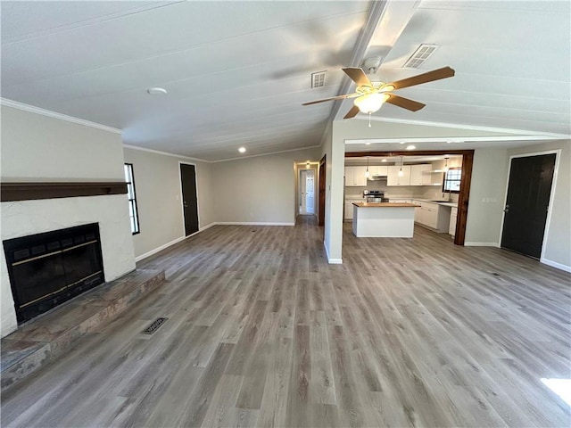 unfurnished living room with a fireplace with raised hearth, light wood finished floors, vaulted ceiling, and baseboards