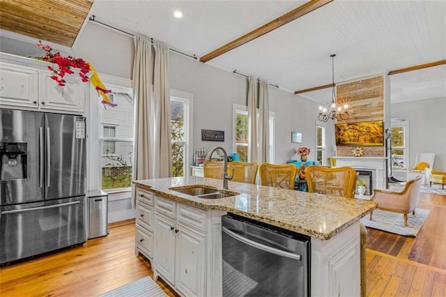 kitchen with hanging light fixtures, sink, an island with sink, appliances with stainless steel finishes, and white cabinetry