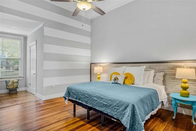 bedroom with wooden walls, hardwood / wood-style flooring, ceiling fan, and ornamental molding