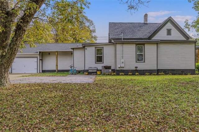 rear view of property featuring a lawn and a garage