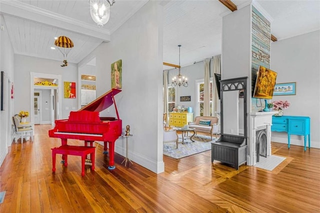 misc room with a towering ceiling, a large fireplace, beam ceiling, a notable chandelier, and hardwood / wood-style floors