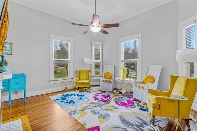 living area with light wood-type flooring, ceiling fan, and crown molding