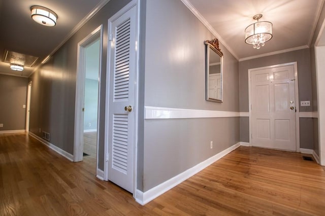 interior space with visible vents, wood finished floors, baseboards, and ornamental molding