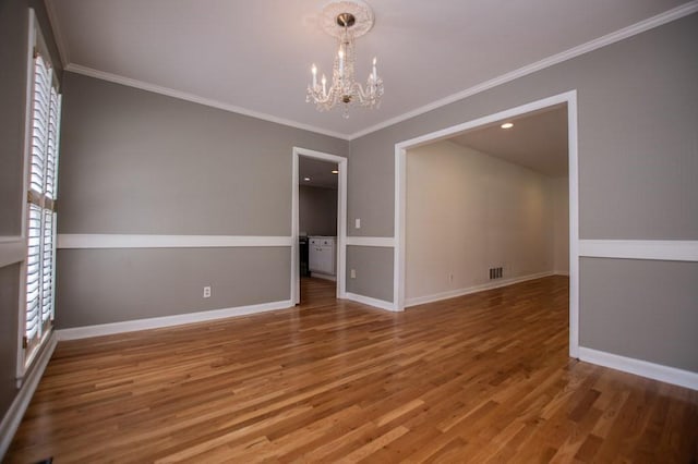 spare room featuring baseboards, wood finished floors, a chandelier, and ornamental molding