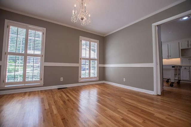 spare room with wood finished floors, baseboards, and ornamental molding