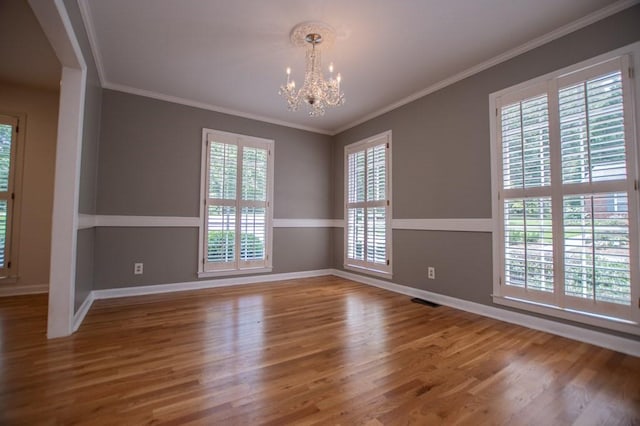 empty room with crown molding, a notable chandelier, and wood finished floors