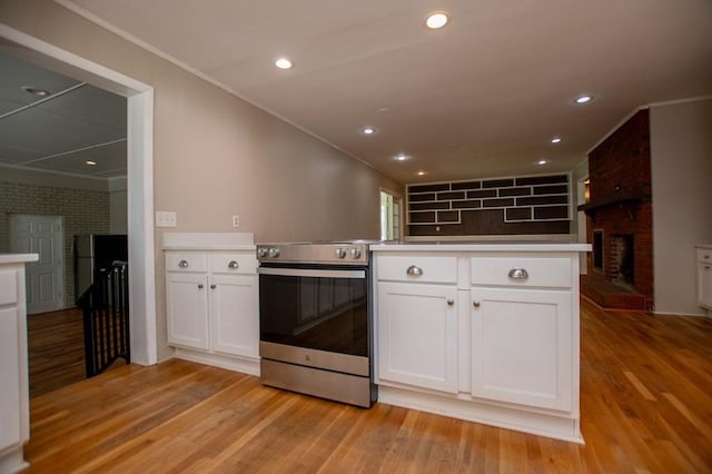 kitchen featuring crown molding, appliances with stainless steel finishes, a fireplace, and white cabinetry