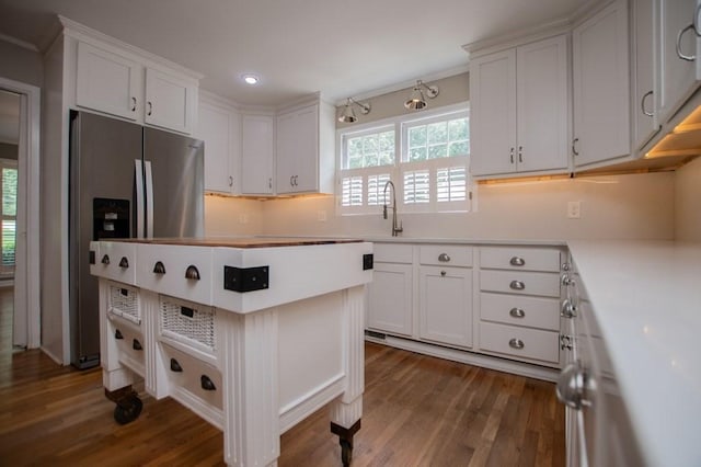 kitchen with dark wood finished floors, stainless steel fridge with ice dispenser, a sink, light countertops, and white cabinetry