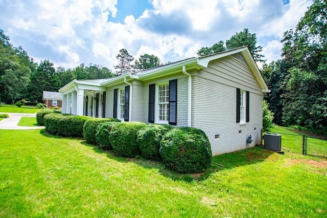 view of property exterior featuring fence, a yard, central AC, crawl space, and brick siding