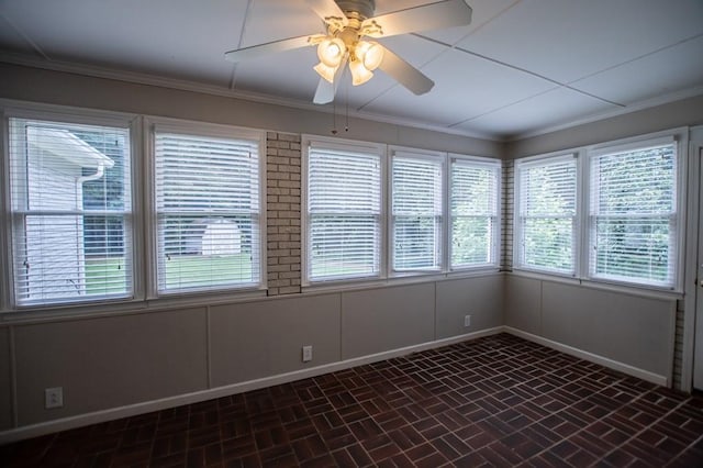 spare room featuring a healthy amount of sunlight, crown molding, and baseboards