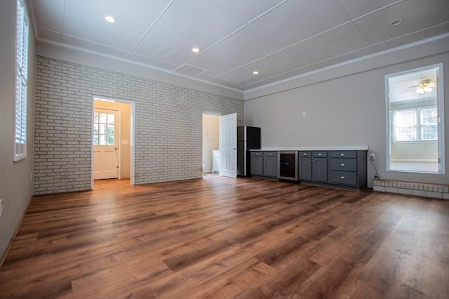 unfurnished living room featuring dark wood-type flooring, a baseboard heating unit, recessed lighting, wine cooler, and brick wall