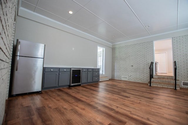 interior space with visible vents, beverage cooler, ornamental molding, dark wood-style floors, and brick wall