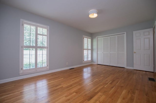 unfurnished bedroom with visible vents, baseboards, light wood-style floors, and a closet