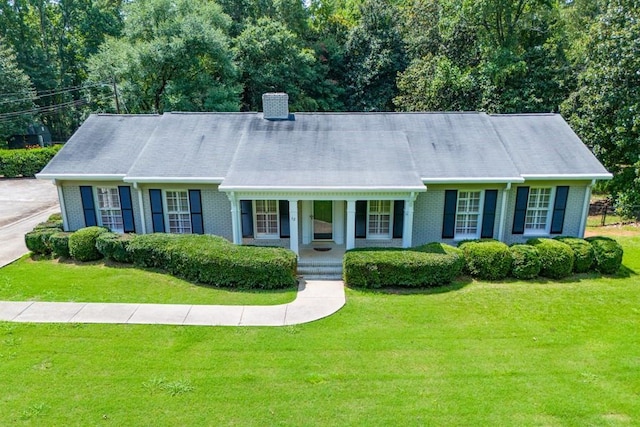 view of front of home featuring a front yard, a porch, brick siding, and a chimney