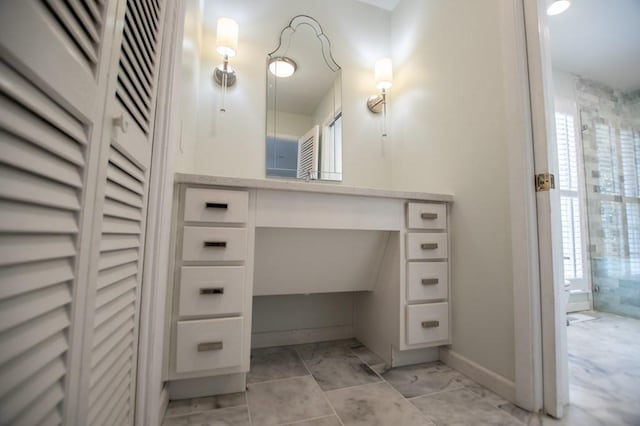 interior space with baseboards, a shower stall, and vanity