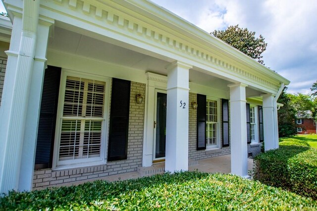 entrance to property with brick siding and a porch