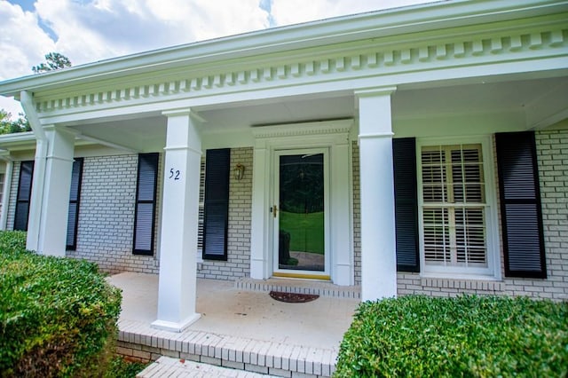 entrance to property featuring brick siding and a porch