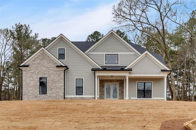 exterior space featuring stone siding, a front lawn, and french doors