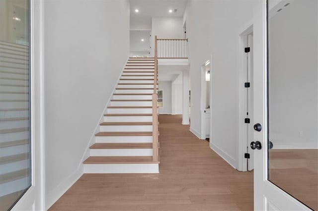 foyer entrance featuring recessed lighting, a high ceiling, baseboards, stairway, and light wood finished floors