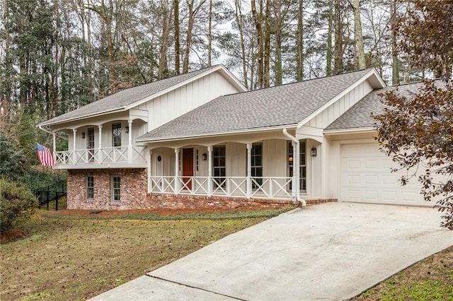 split level home with a porch, a shingled roof, driveway, and a garage