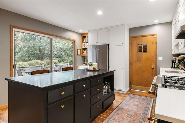 kitchen with light wood-style flooring, high quality fridge, white cabinets, and dark cabinetry