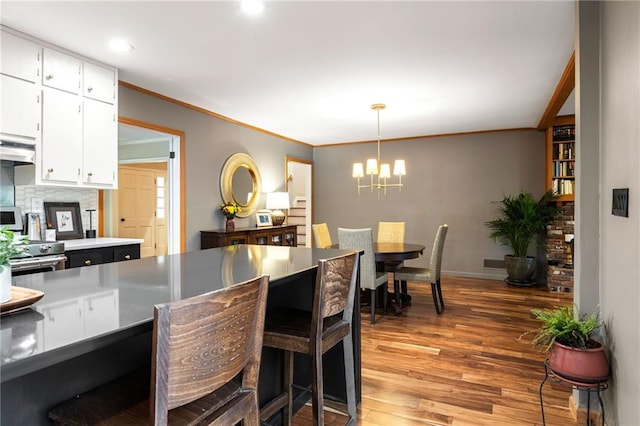 dining room with recessed lighting, an inviting chandelier, light wood-style floors, ornamental molding, and baseboards