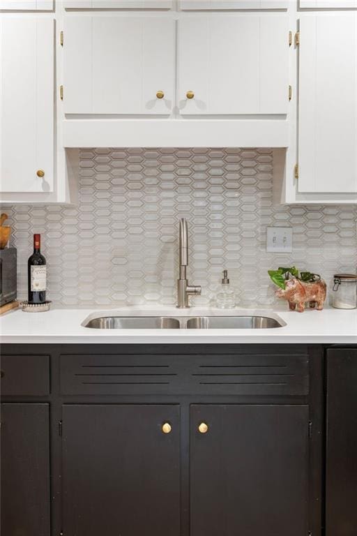 kitchen featuring tasteful backsplash, white cabinets, light countertops, and a sink