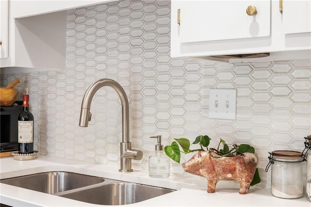 room details featuring light countertops, a sink, backsplash, and white cabinetry