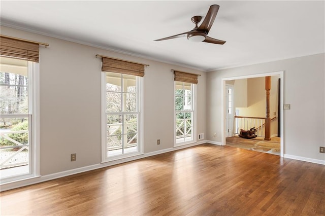 spare room featuring crown molding, baseboards, and wood finished floors